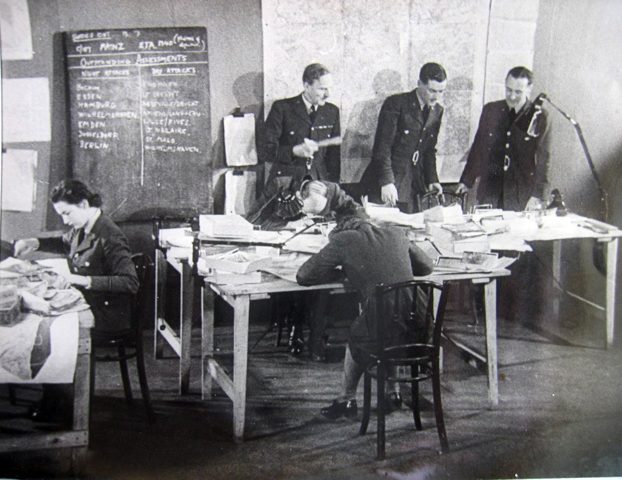 Bill Hunter (standing at the table, centre) in the RAF’s Central Information Unit office, July 1942. (c) Andrew Hunter